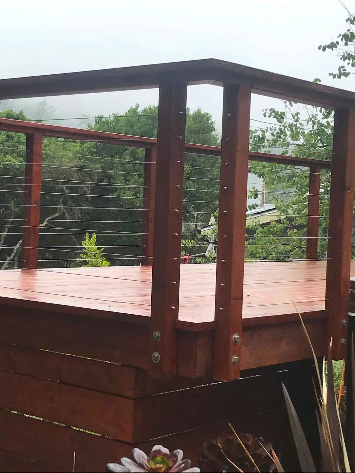 Finished elevated deck with cable railing in coastal fog